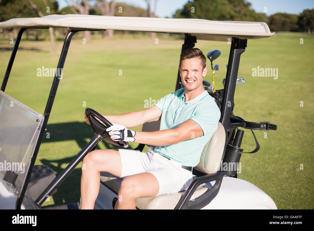 Glücklich Golfer Mann Golfbuggy fahren Stockfoto
