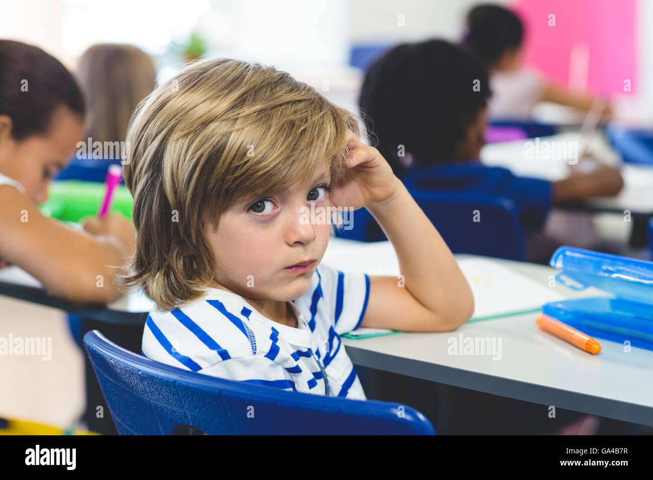 Ernste junge mit Klassenkameraden im Klassenzimmer Stockfoto