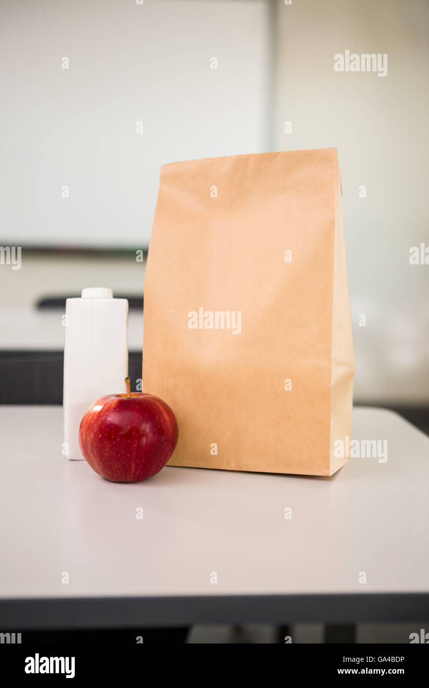 Apfel mit Getränk Flasche und Papier Tasche auf Tisch im Klassenzimmer Stockfoto