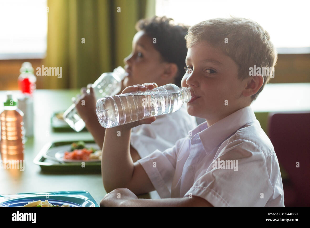 Porträt von Schuljunge Trinkwasser aus der Flasche Stockfoto