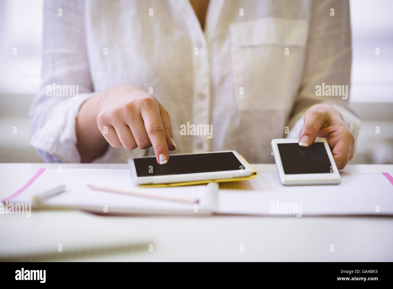 Mittelteil der Geschäftsfrau mit drahtlosen Technologien am Schreibtisch im Büro Stockfoto