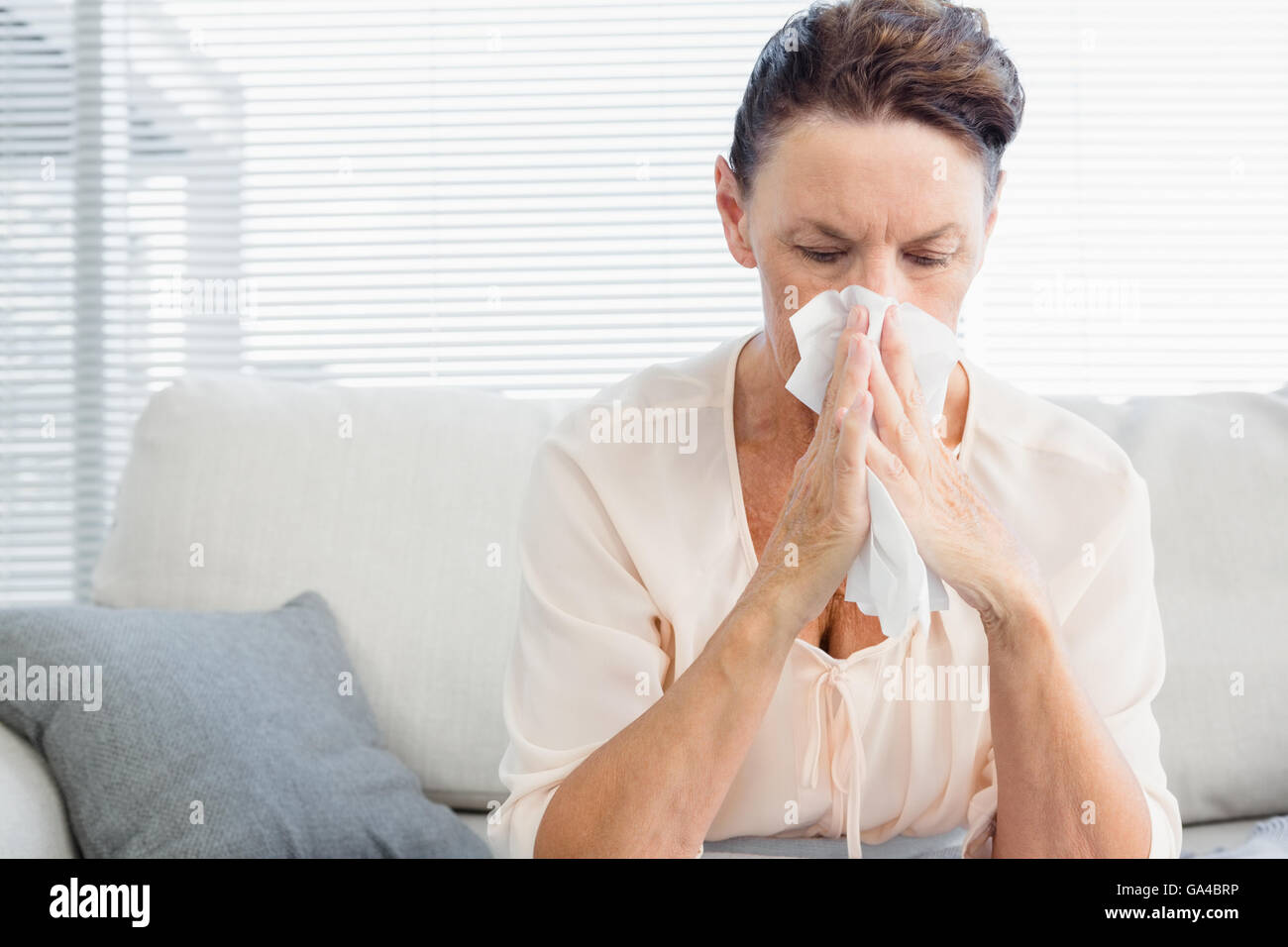 Reife Frau leiden unter Kälte sitzend auf sofa Stockfoto