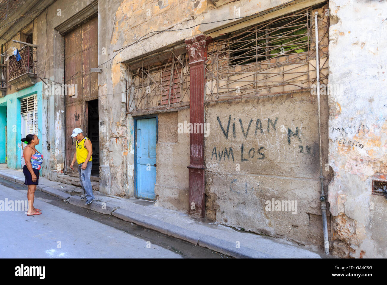 Straßenszene mit Einheimischen plaudern unter die Dilapitated Gebäude in Inquisidor Straße, Habana Vieja, Alt-Havanna, Kuba Stockfoto