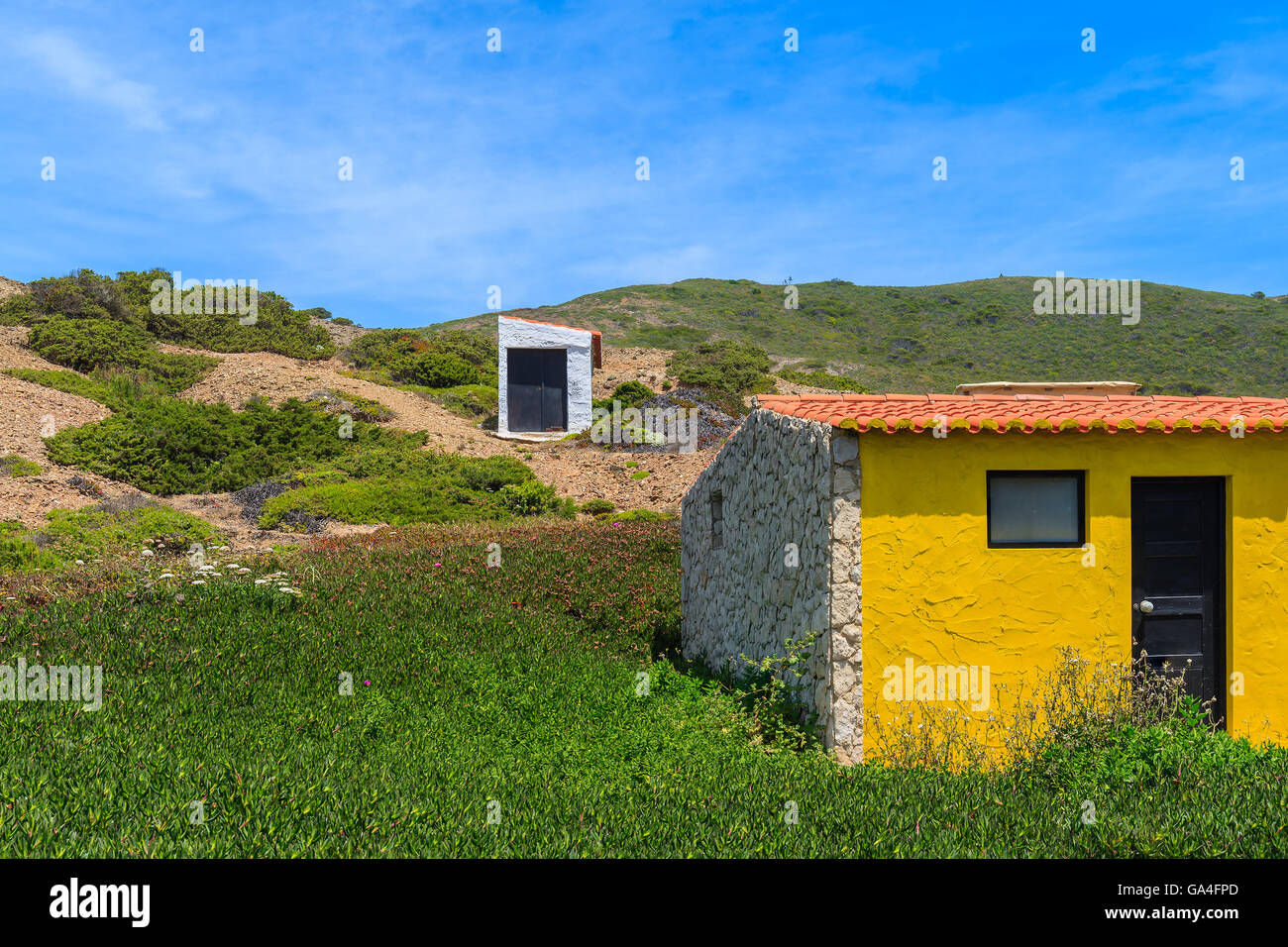 Kleine Häuser auf grünem Hügel gebaut für Surfer am Castelejo Strand auf der Küste von Portugal Stockfoto