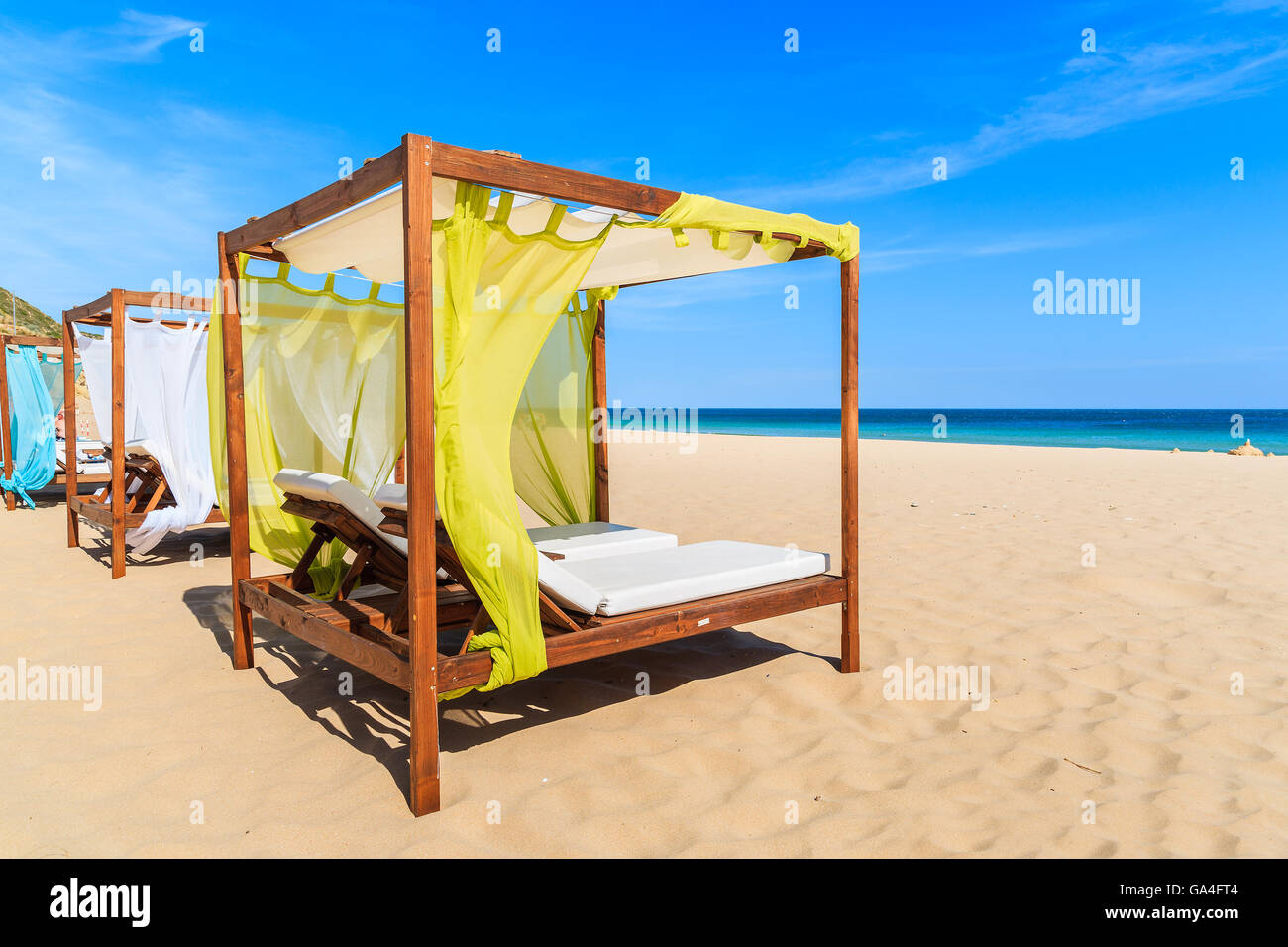 Liegestühle am goldenen Sandstrand in der Stadt Salema, Portugal Stockfoto