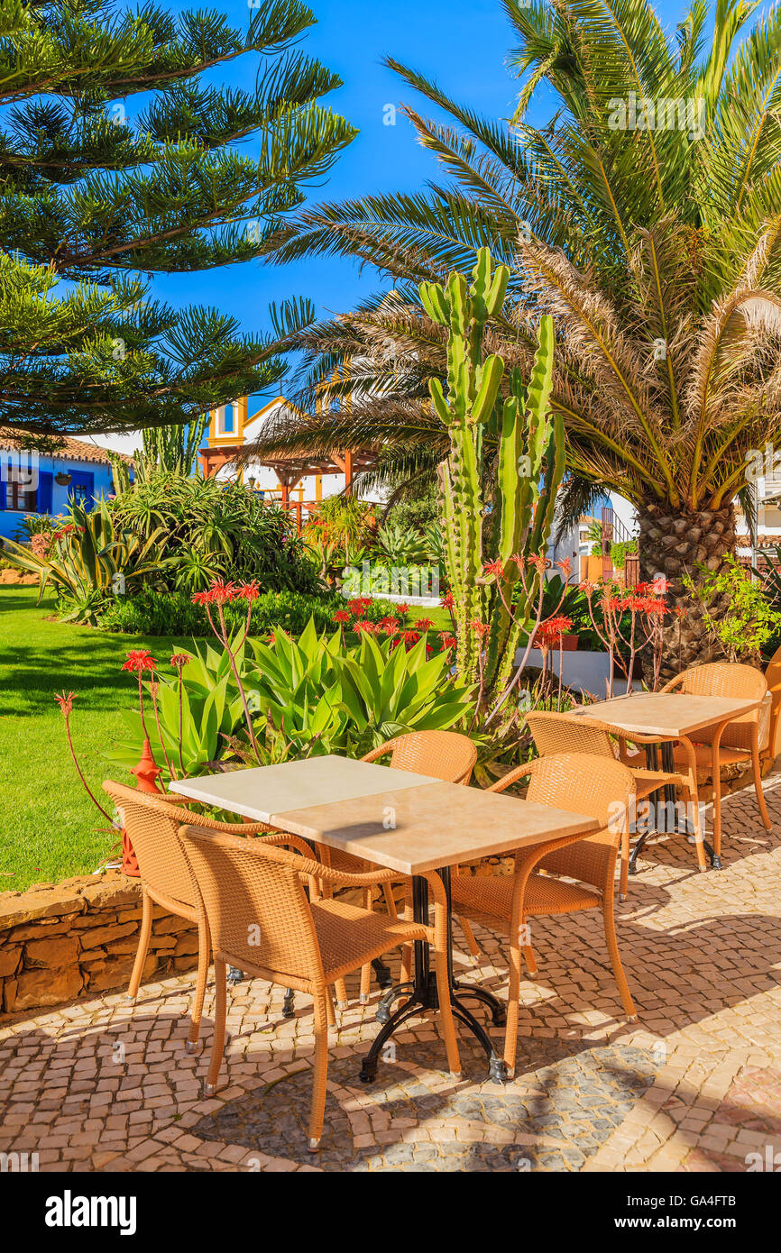 Tische mit Stühlen in grüne Parkanlage der Stadt Luz, Badeort in der Region Küste der Algarve, Portugal Stockfoto