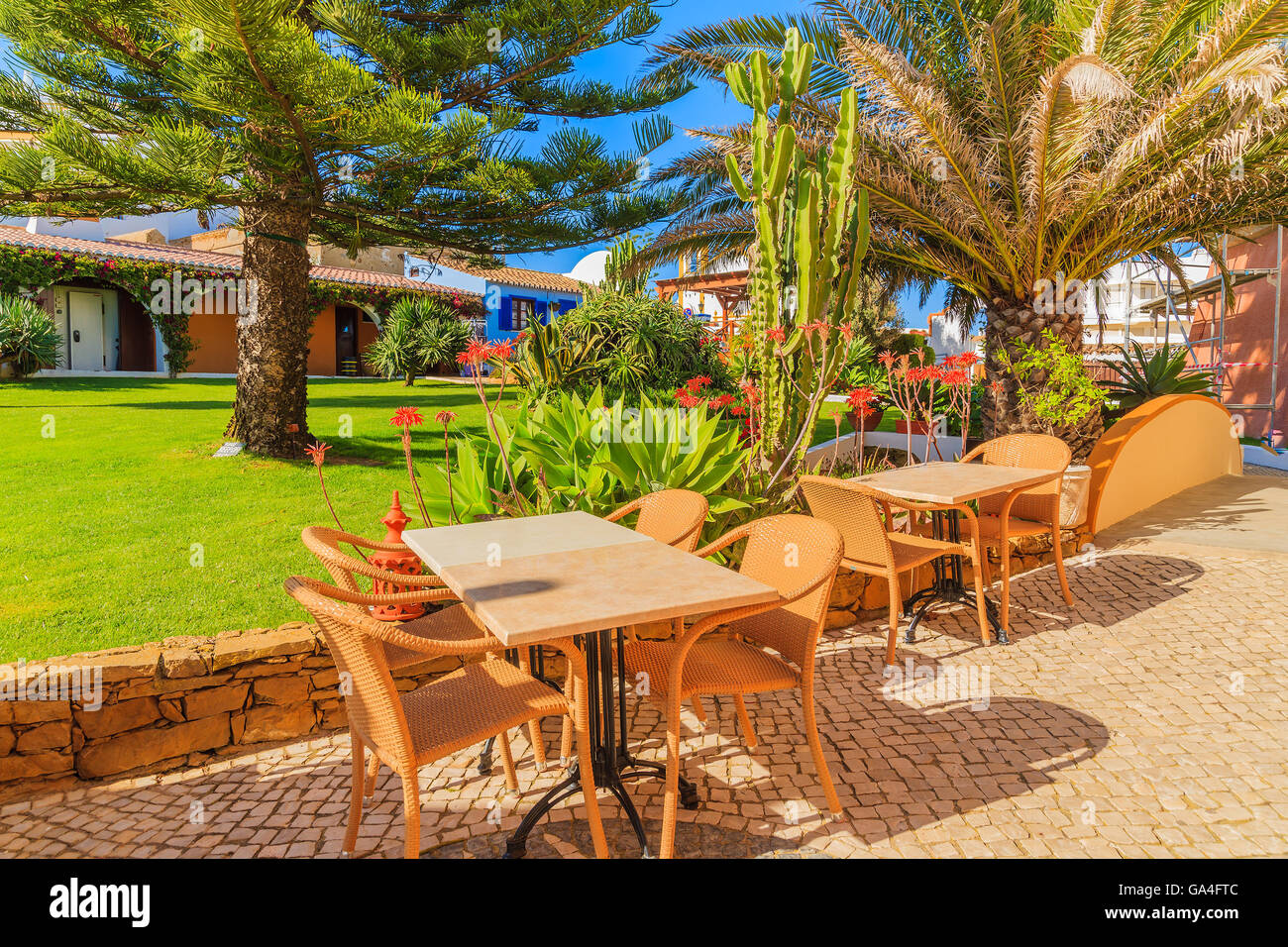 Tische mit Stühlen in grüne Parkanlage der Stadt Luz, Badeort in der Region Küste der Algarve, Portugal Stockfoto