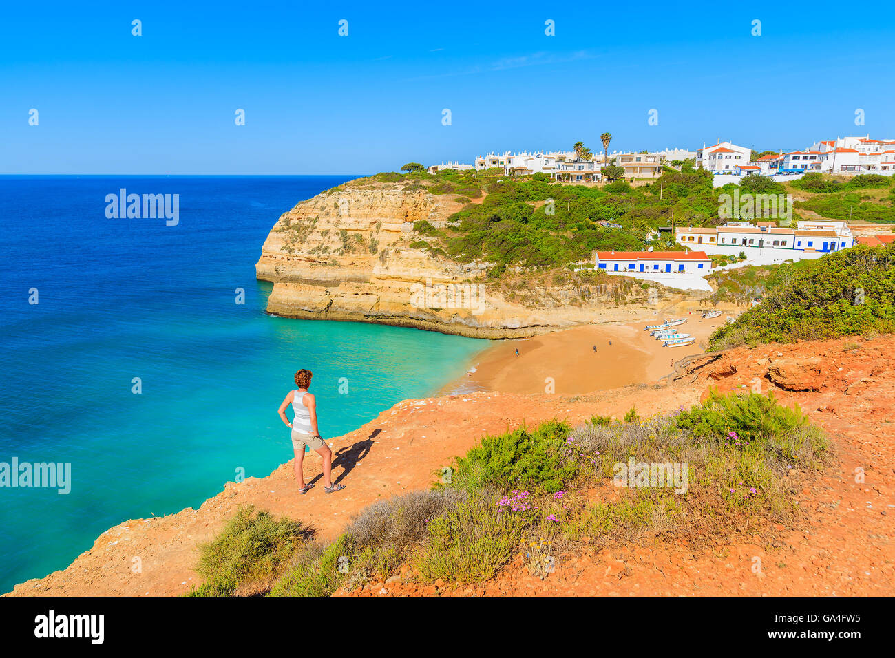 Junge Frau Tourist auf Klippe stehend und mit Blick auf Benagil Strand, Algarve, Portugal Stockfoto