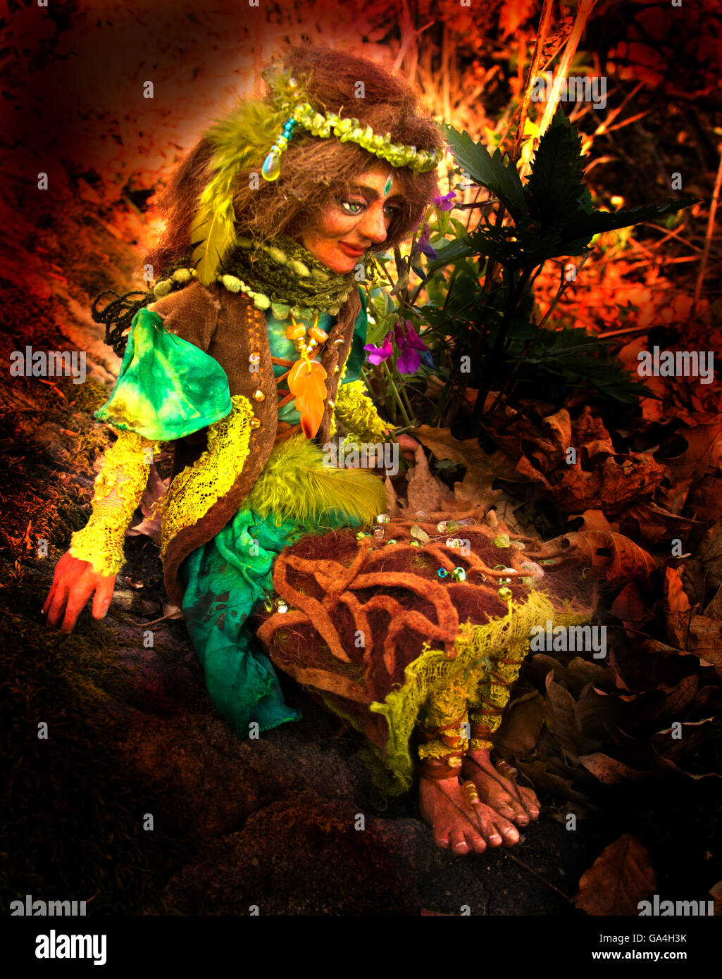 Erde Fee Puppe Figur sitzt auf einem Stein im Wald Stockfoto