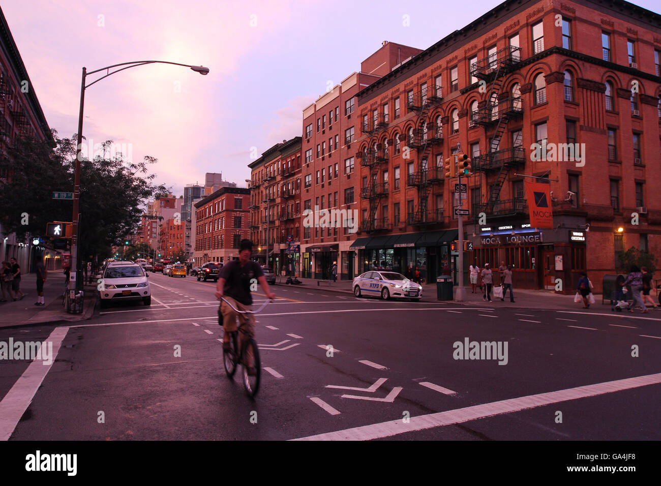 Radfahrer Fahrradtouren auf Frederick Douglas Blvd. in der Nähe von Mehrfamilienhäusern in Harlem New York bei Sonnenuntergang im Sommer. Stockfoto