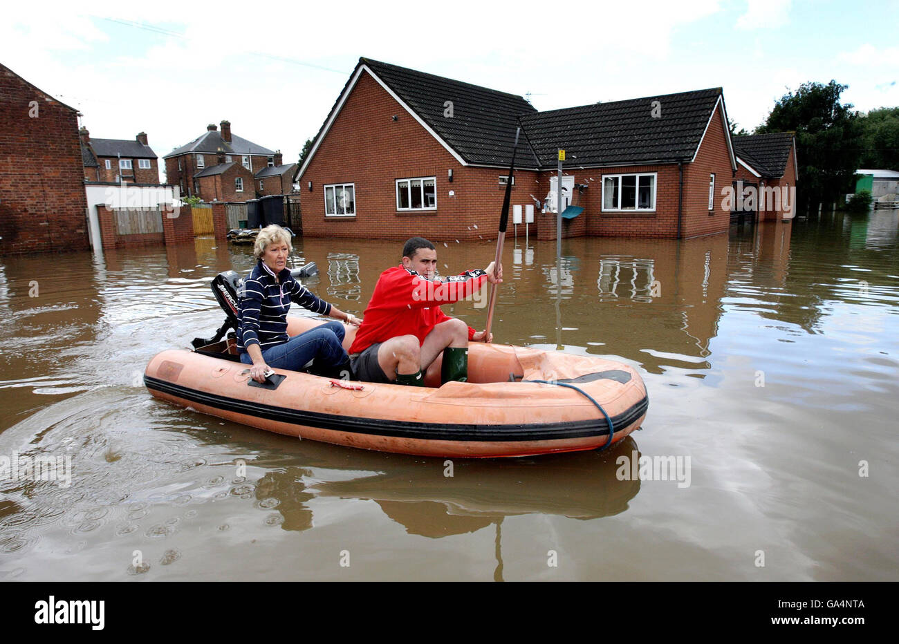 Stürme trafen Großbritannien. Eine Frau wird von ihrem Haus auf einen trockenen Boden in einem überfluteten Gebiet in der Nähe des Flusses Severn in Gloucester gebracht. Stockfoto