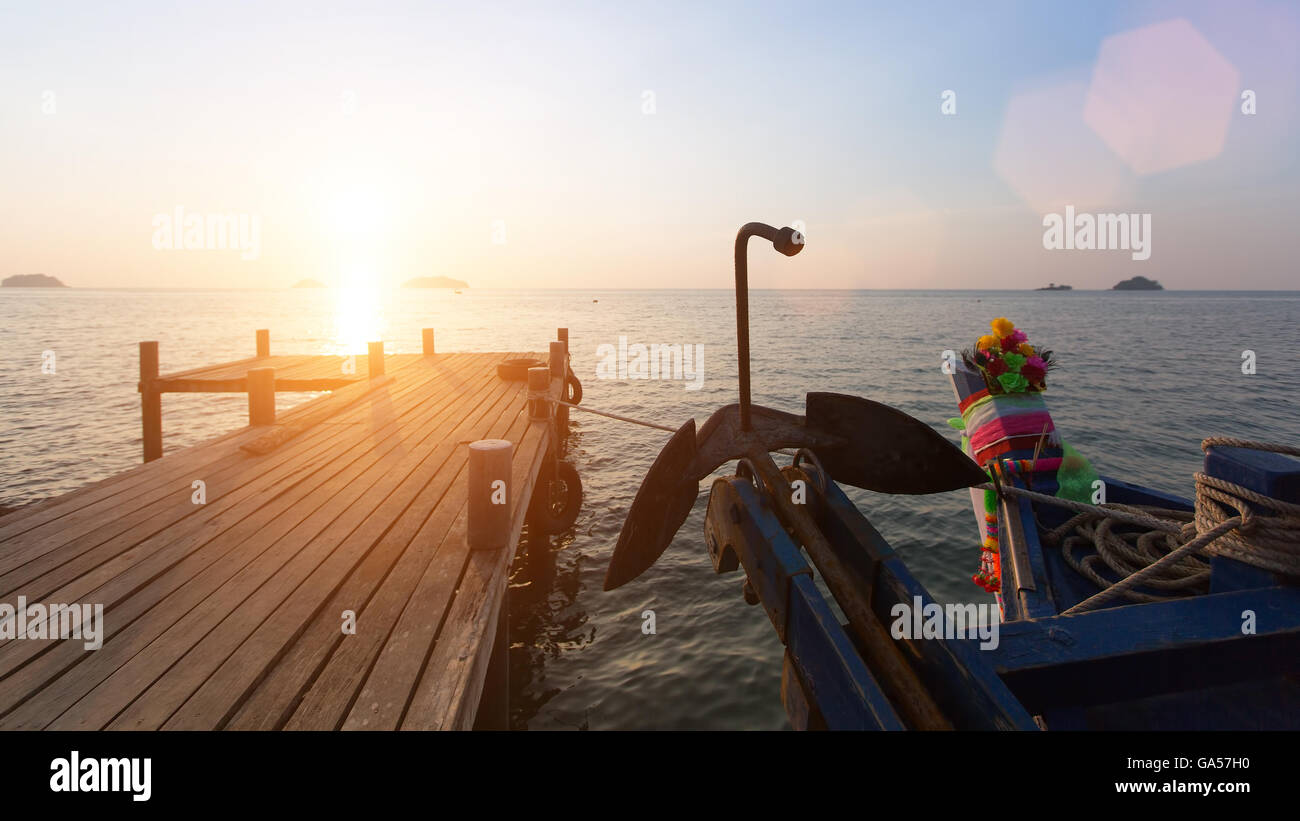 Hölzerne Pier und Thai Boot während des Sonnenuntergangs. Stockfoto