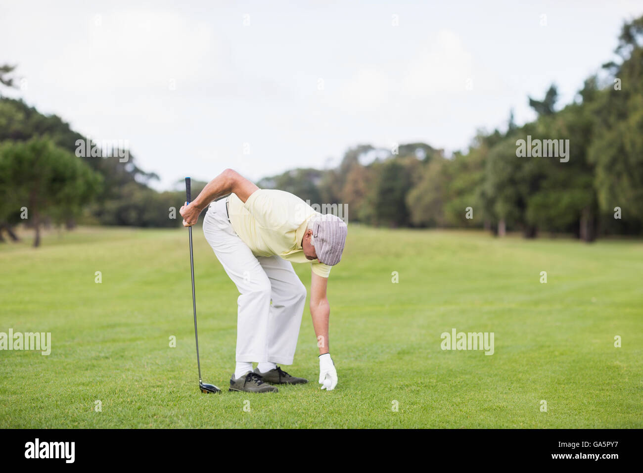 Reifer Mann halten Golfclub beim Biegen Stockfoto