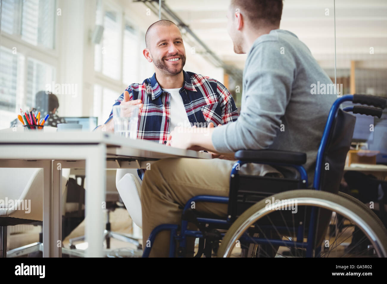 Handicap Geschäftsmann mit Kollegen im Büro sitzen Stockfoto