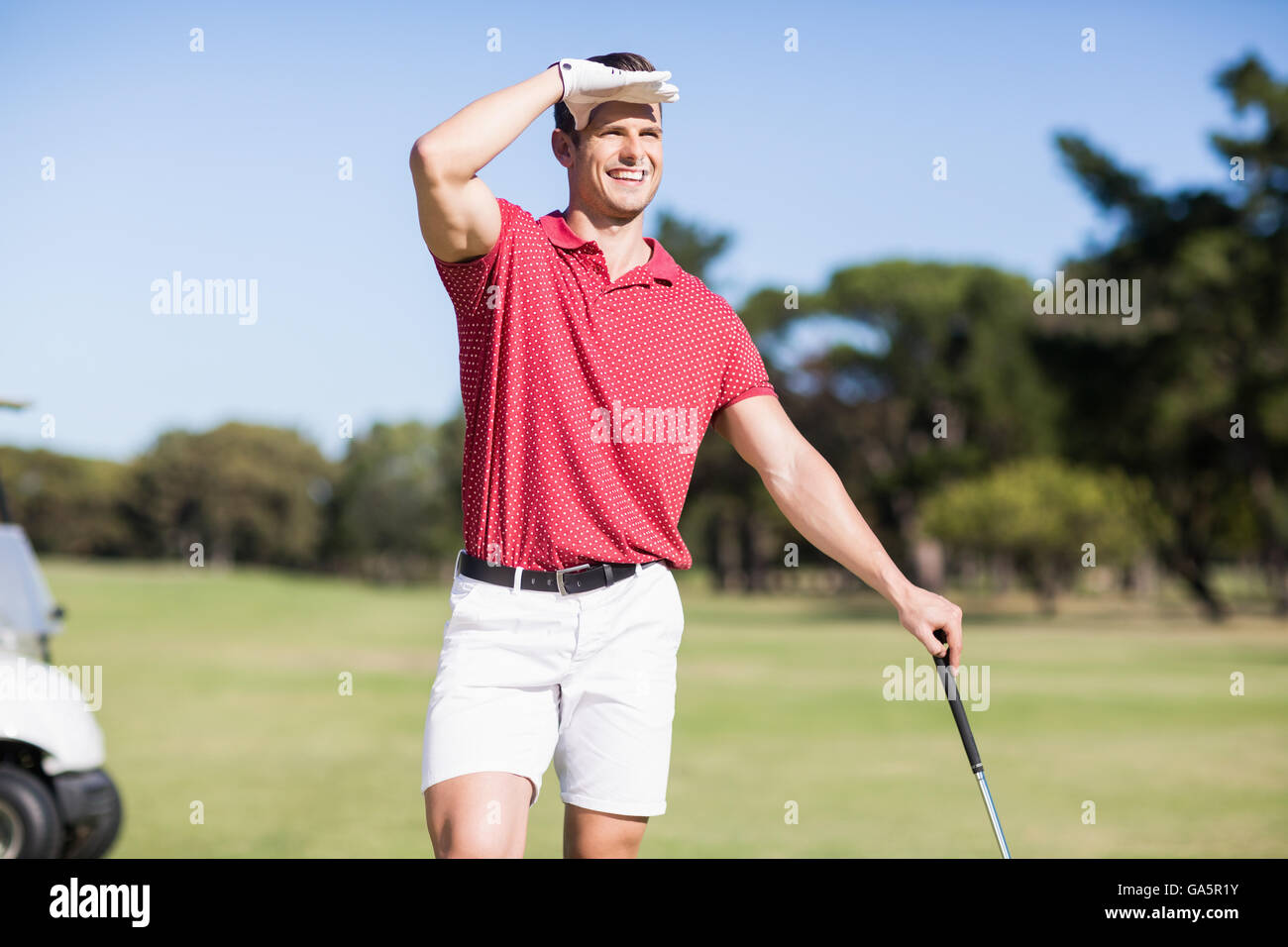 Golfer, die Abschirmung Augen Lächeln Stockfoto