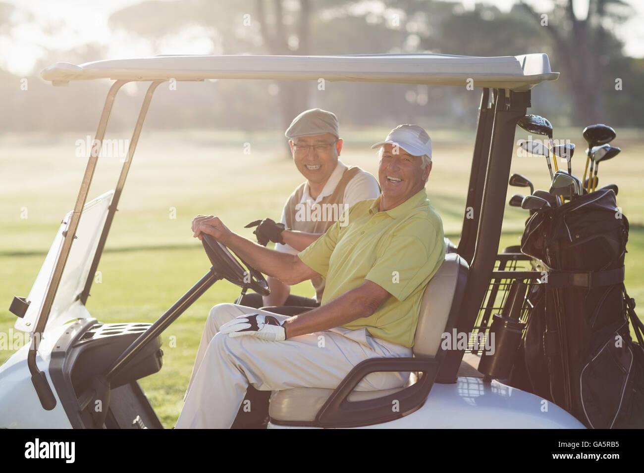 Porträt von fröhlichen Golfer Freunde sitzen in Golfwagen Stockfoto