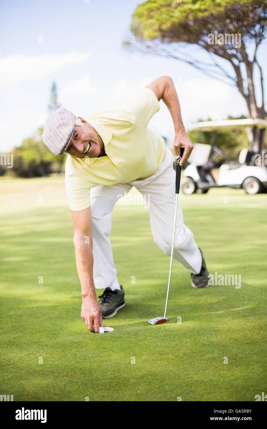 Glücklich reifer Mann halten Golfclub beim Biegen auf Wiese Stockfoto