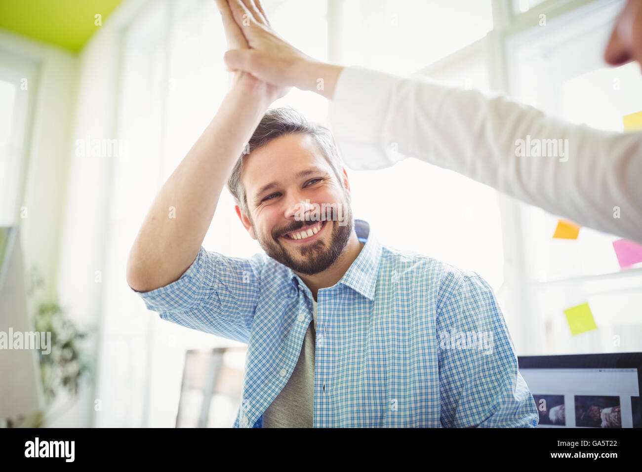 Lächelnde Mitarbeiter geben High-Five in Kreativbüro Stockfoto