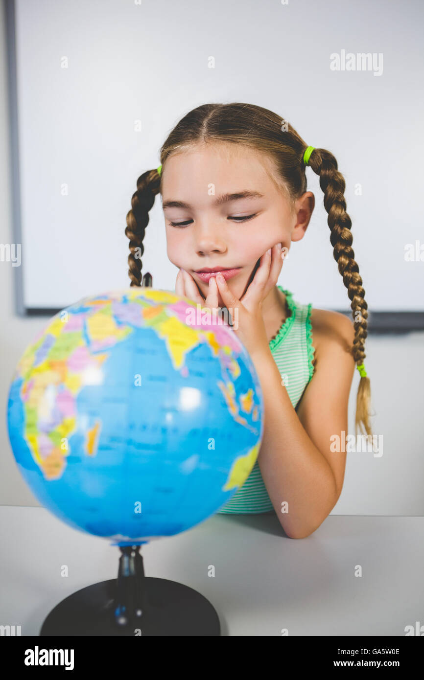 Schulmädchen Blick auf Globus im Klassenzimmer Stockfoto