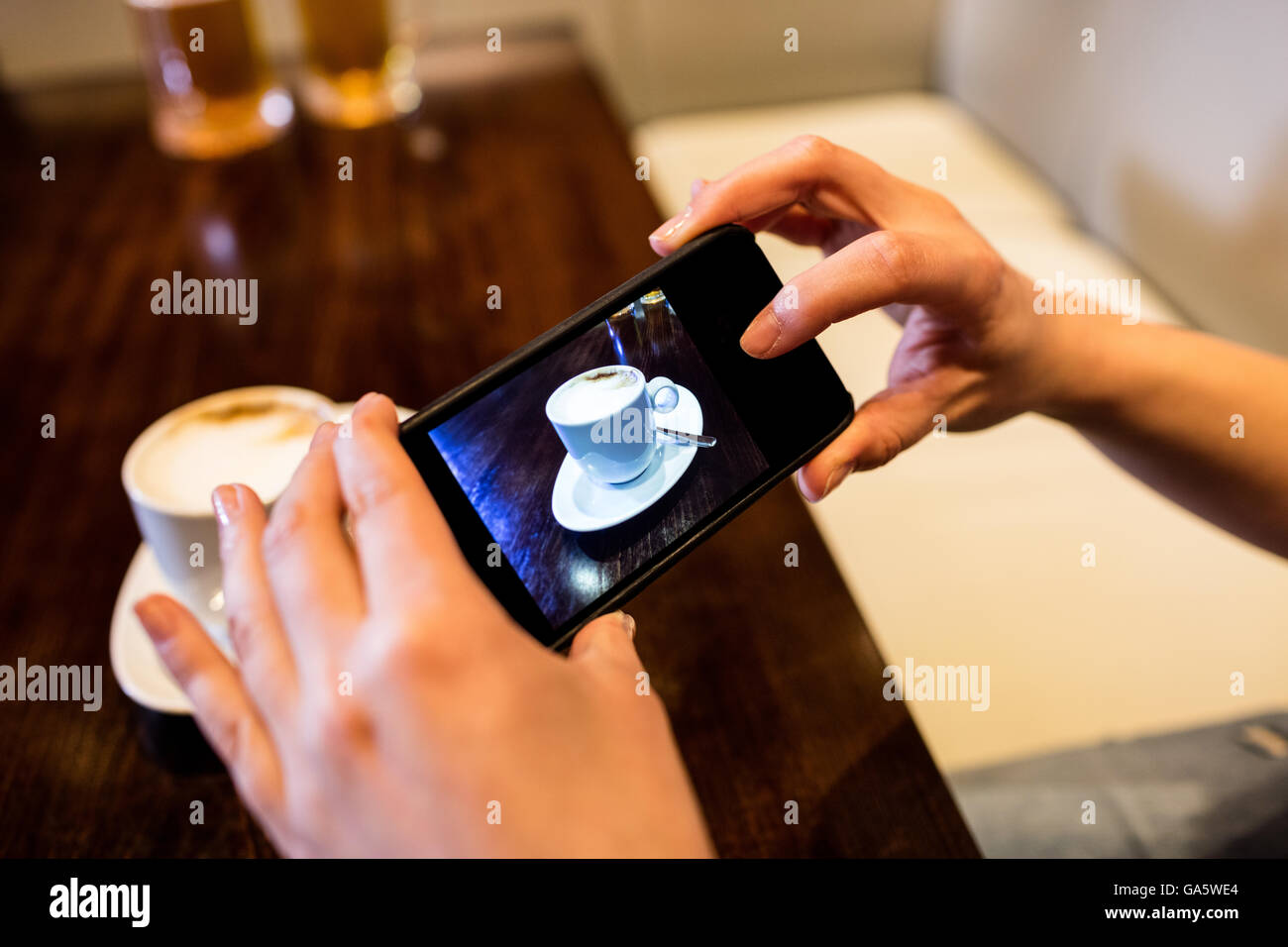 Frau fotografieren Kaffeetasse auf Tisch Stockfoto