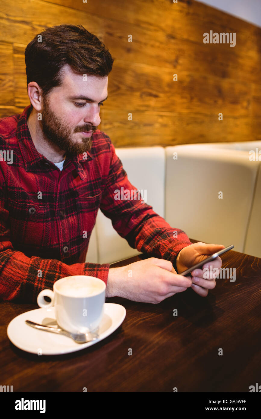 Mann mit Handy von Kaffeetasse im restaurant Stockfoto