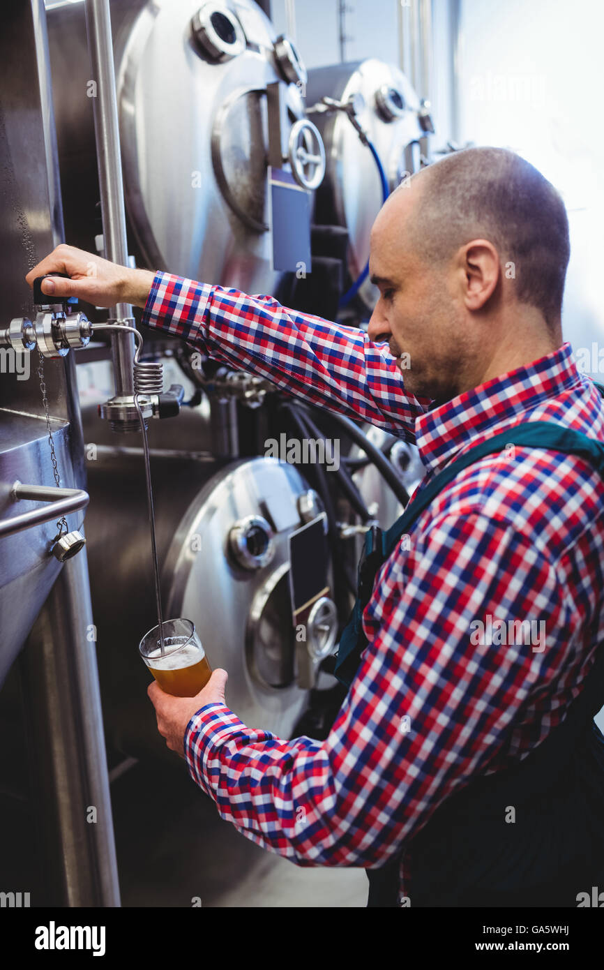 Hersteller füllen Bier aus Vorratsbehälter in der Destillerie Stockfoto