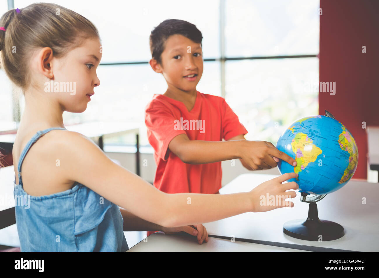 Schülerinnen und Schüler suchen im Globe im Klassenzimmer Stockfoto