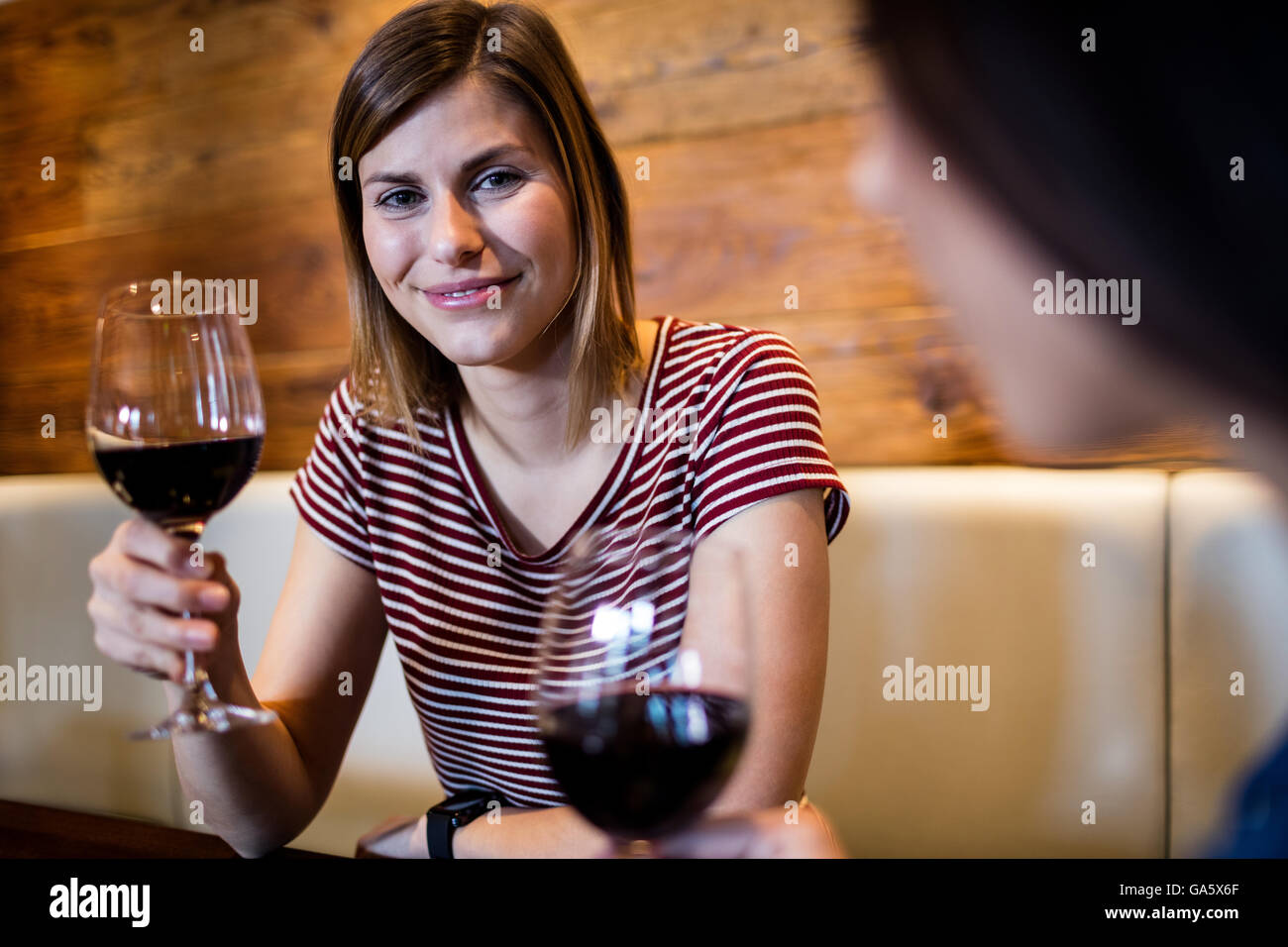 Junge Frau trinkt Wein mit Freund Stockfoto