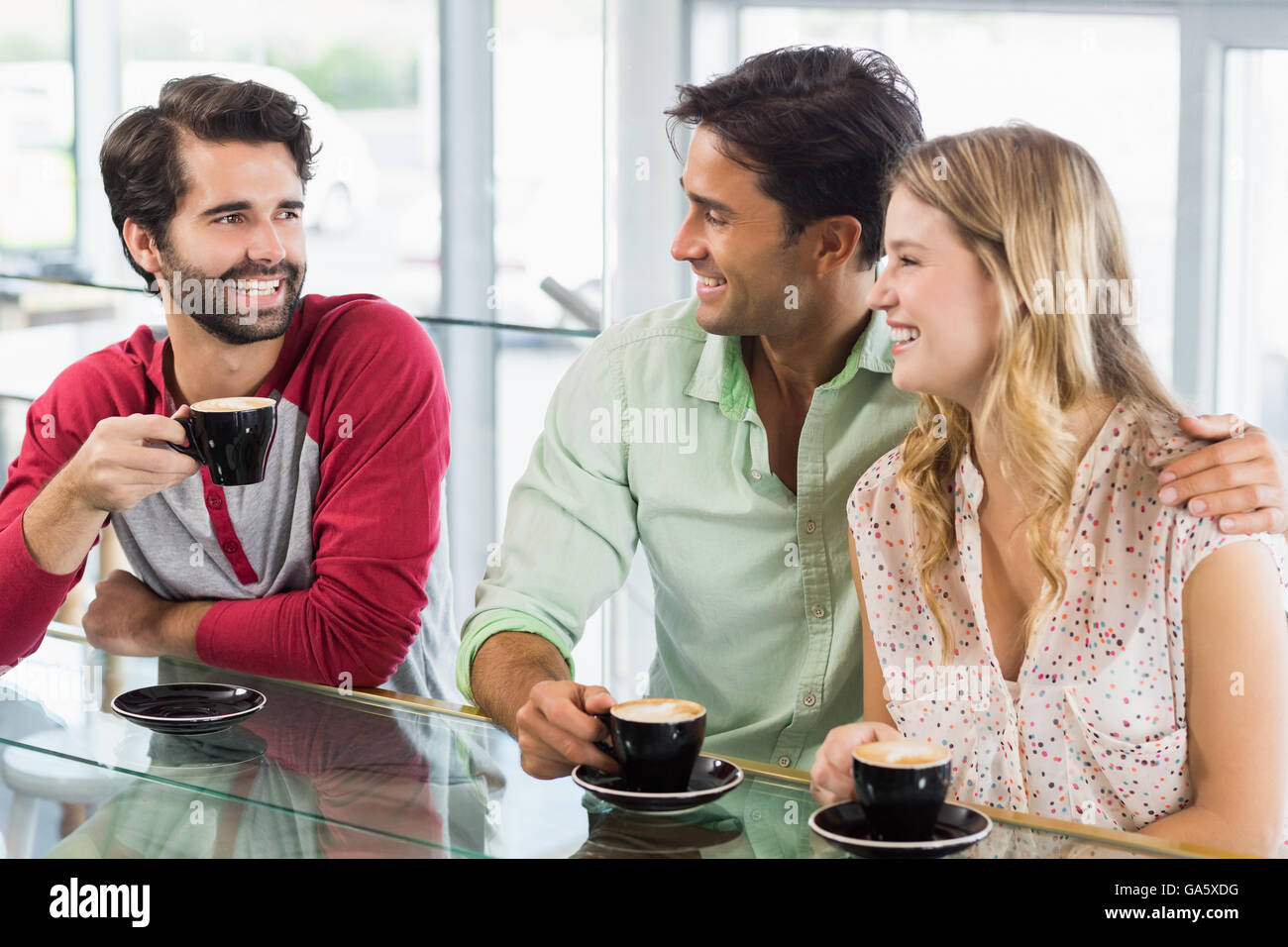 Lächelnde Frau und zwei Männer, die Tasse Kaffee Stockfoto