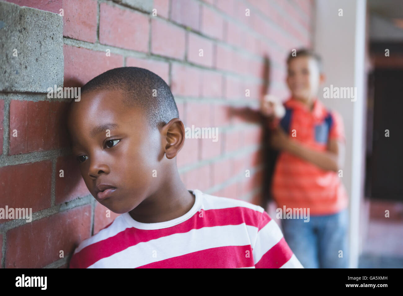 Schulkind Mobbing einen traurigen jungen im Korridor Stockfoto