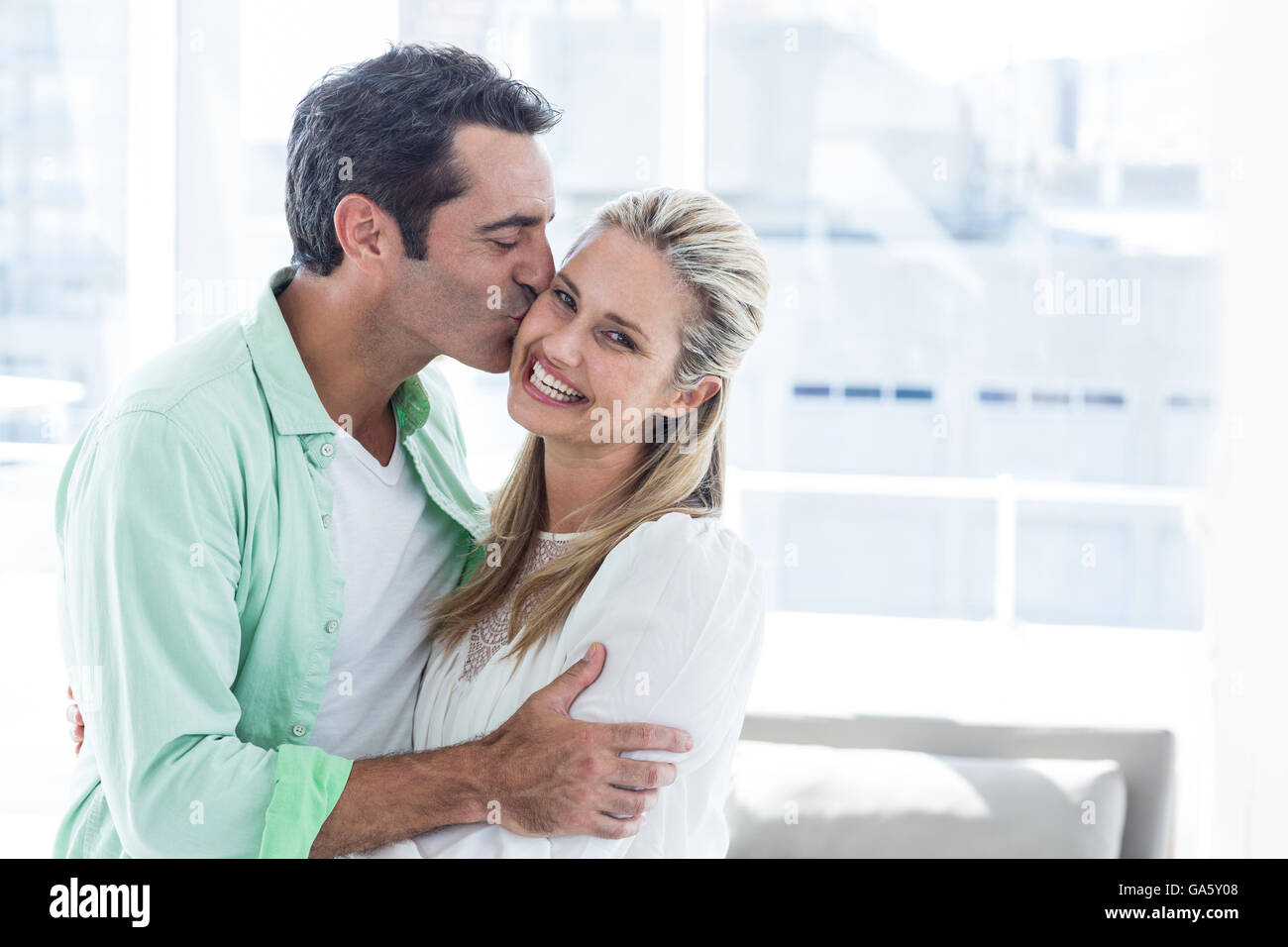 Mitte erwachsener Mann küsst Frau zu Hause Stockfoto