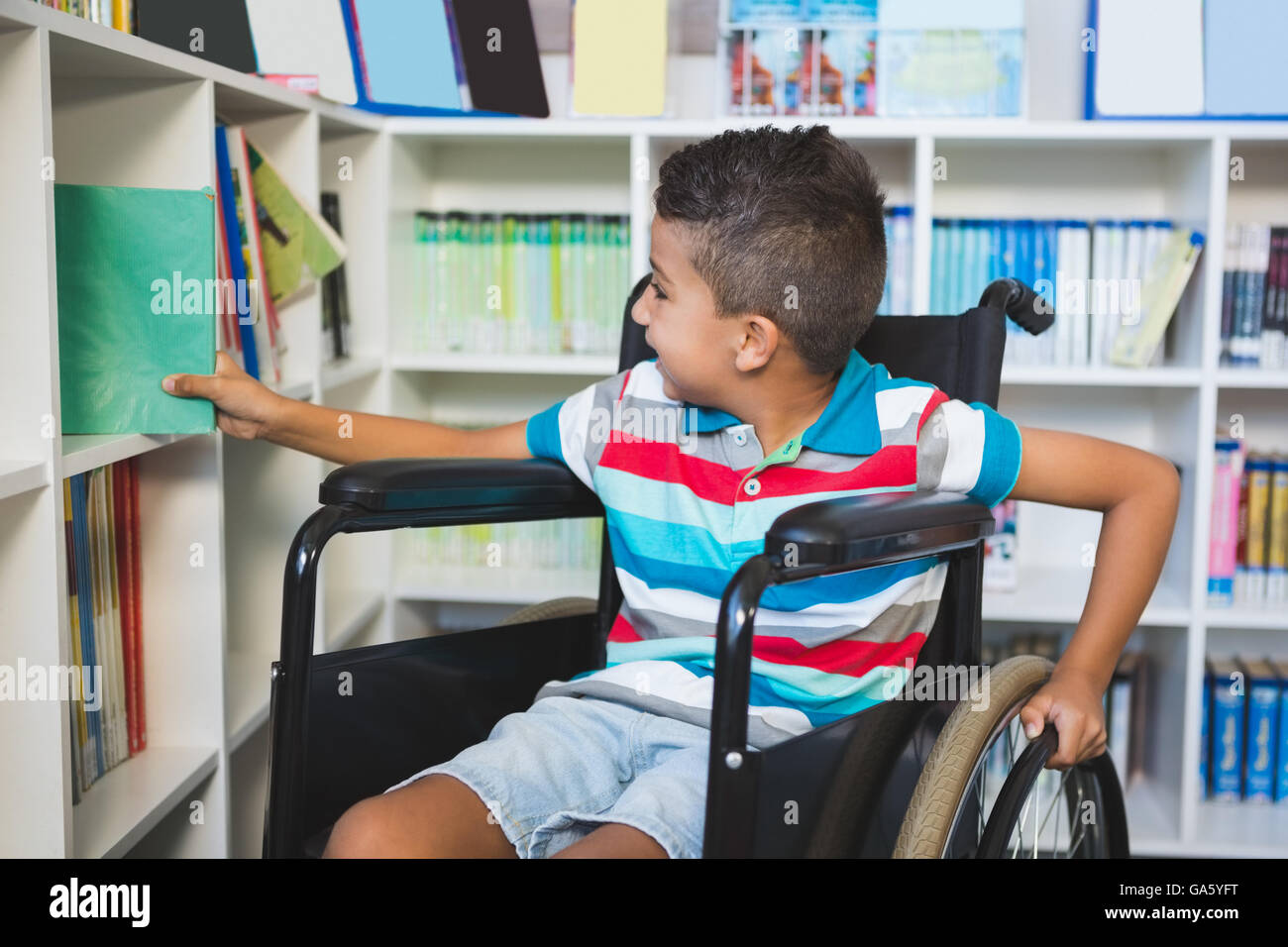 Behinderten jungen Bücherregal in der Bibliothek ein Buch auswählen Stockfoto