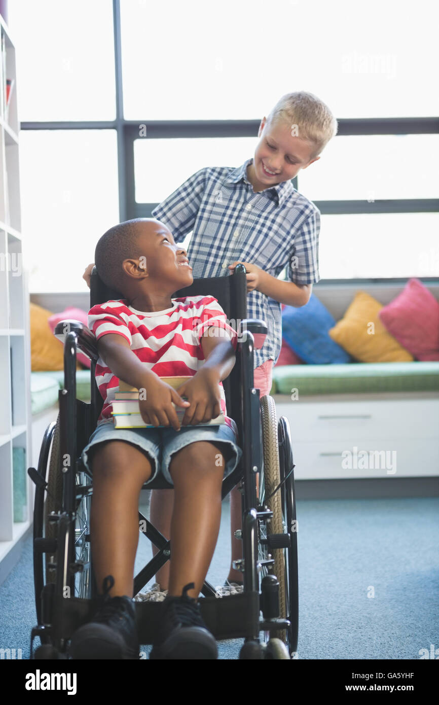 Glückliche Schüler mit seinem Freund im Rollstuhl Stockfoto