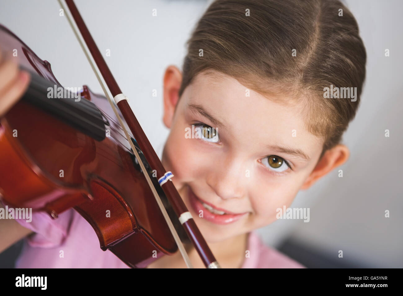 Porträt des Lächelns Schulmädchen spielt Geige im Klassenzimmer Stockfoto