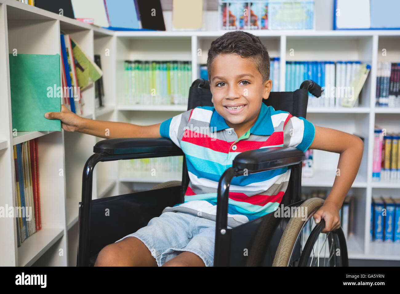 Behinderten jungen Bücherregal in der Bibliothek ein Buch auswählen Stockfoto