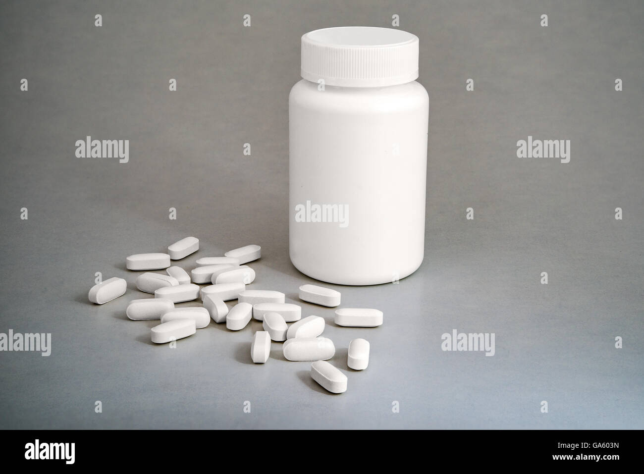 Weiße Kunststoff Medizinfläschchen mit weißen Pillen auf grauem Hintergrund Stockfoto