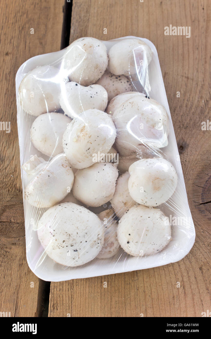 Pilze, verpackt in Cellophan auf Holztisch Stockfoto