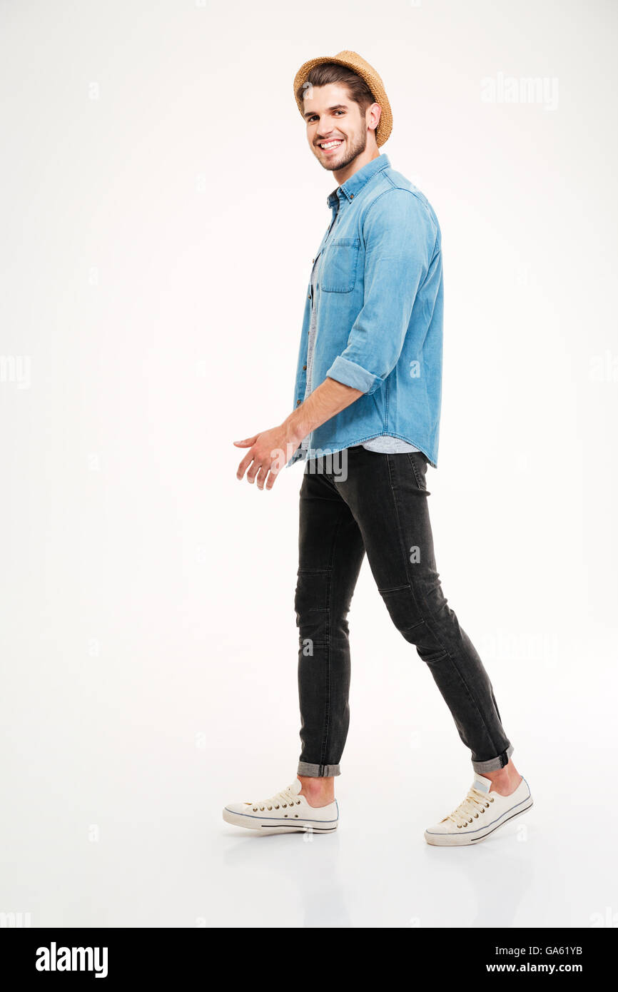 Volle Länge des fröhlichen jungen Mann zu Fuß und lächelnd auf weißem Hintergrund Stockfoto
