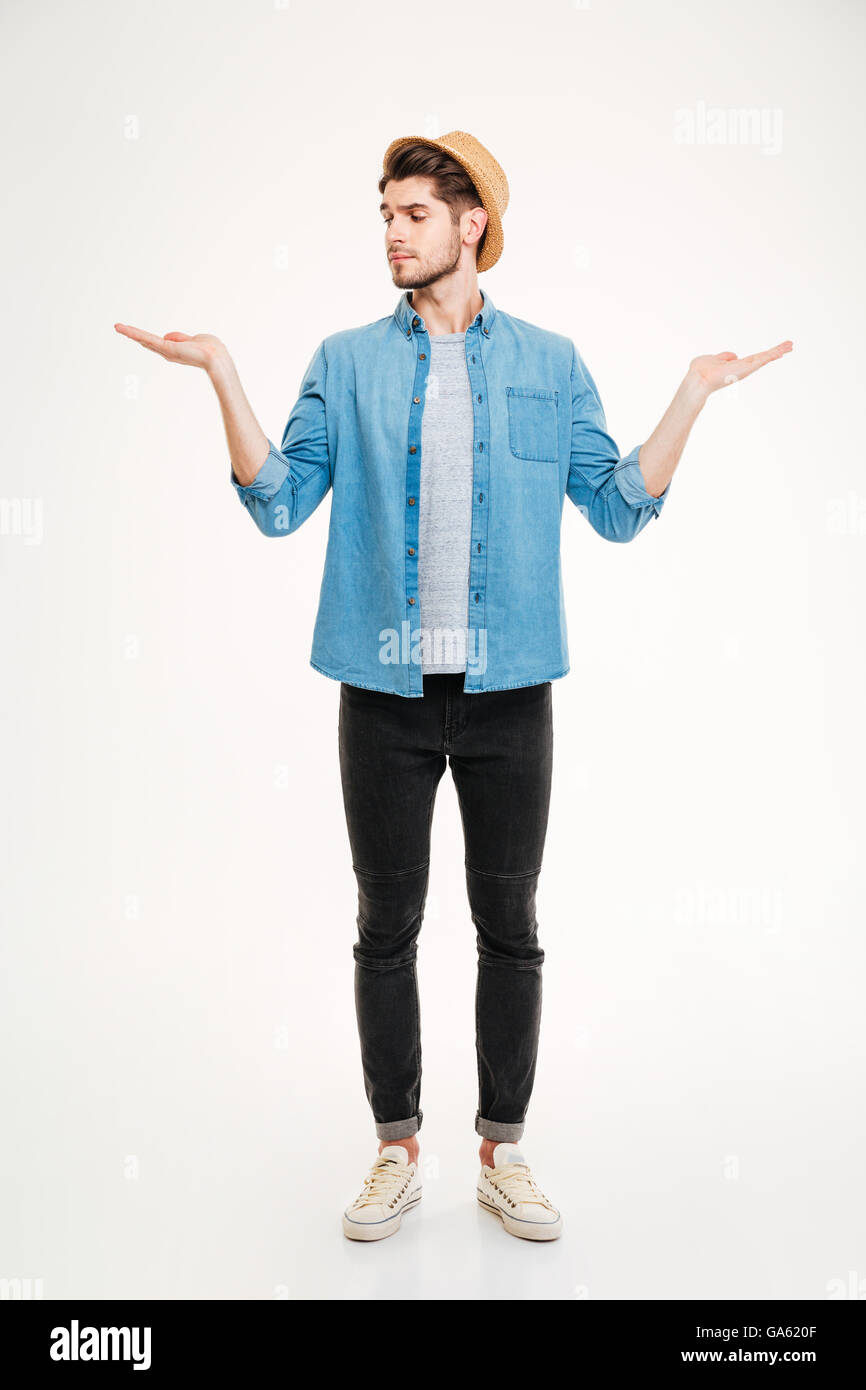 Nachdenklicher junger Mann stehen und halten Exemplar auf beiden Handflächen auf weißem Hintergrund Stockfoto