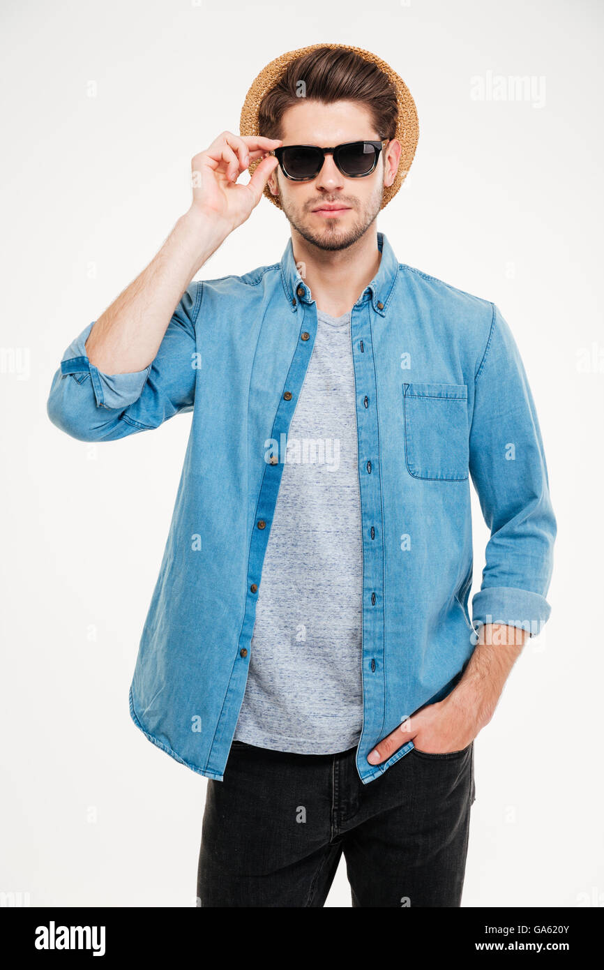 Porträt von zuversichtlich hübscher junger Mann in Hant und Sonnenbrille auf weißem Hintergrund Stockfoto