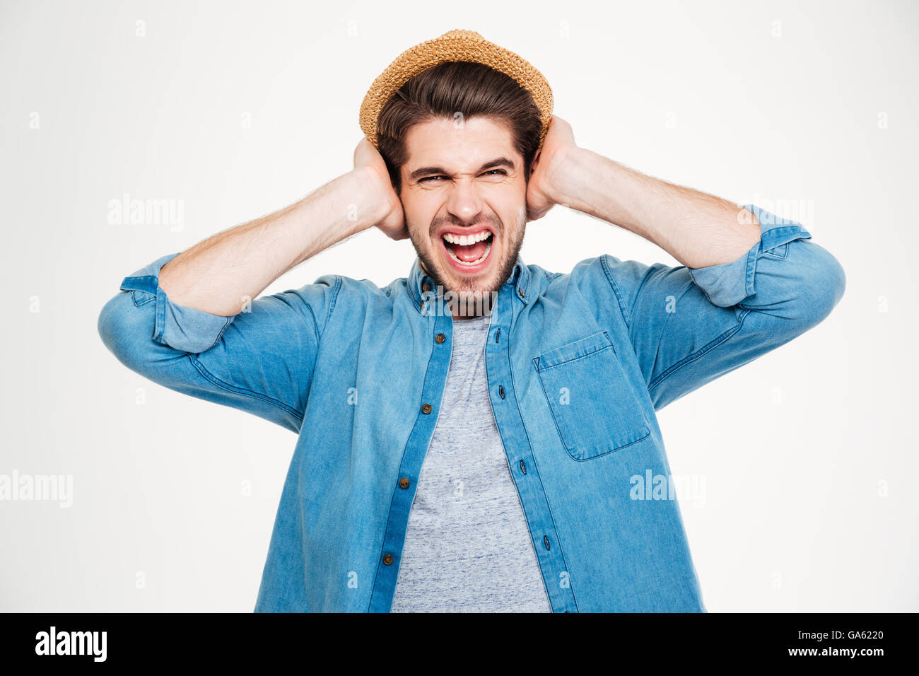 Wahnsinnig gereizt Jüngling bedeckt Ohren von Händen und schreiend auf weißem Hintergrund Stockfoto