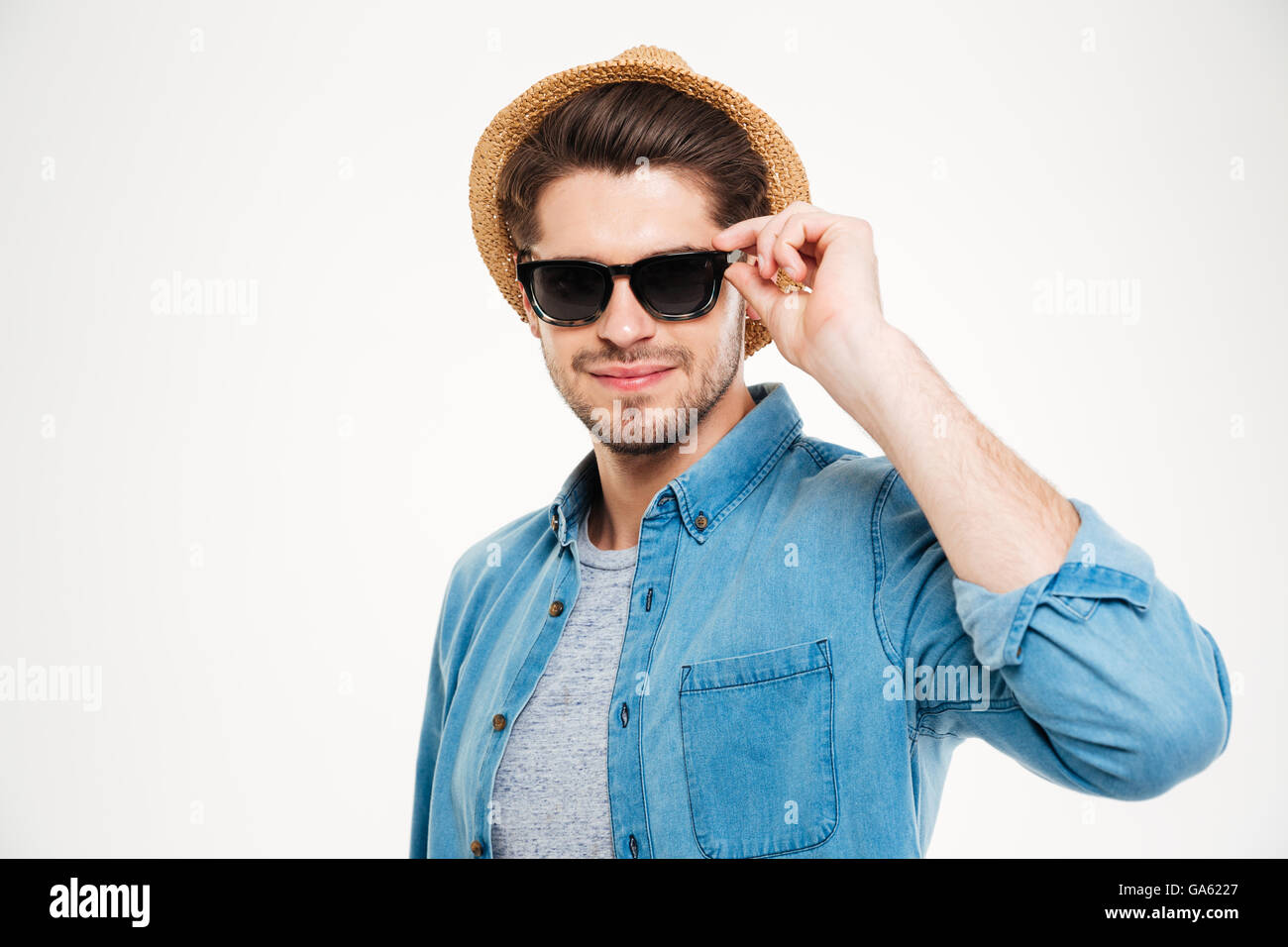 Attraktive zuversichtlich junger Mann mit Hut und Sonnenbrille auf weißem Hintergrund Stockfoto