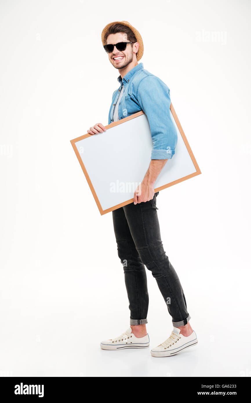 Glücklich lächelnd junger Mann zu Fuß und halten leeres Whiteboard auf weißem Hintergrund Stockfoto