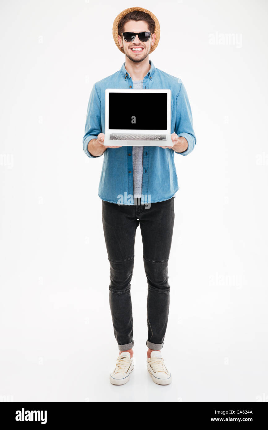 Gesamte Länge der glücklicher junge Mann mit Sonnenbrille und Hut mit schwarzer Bildschirm laptop Stockfoto