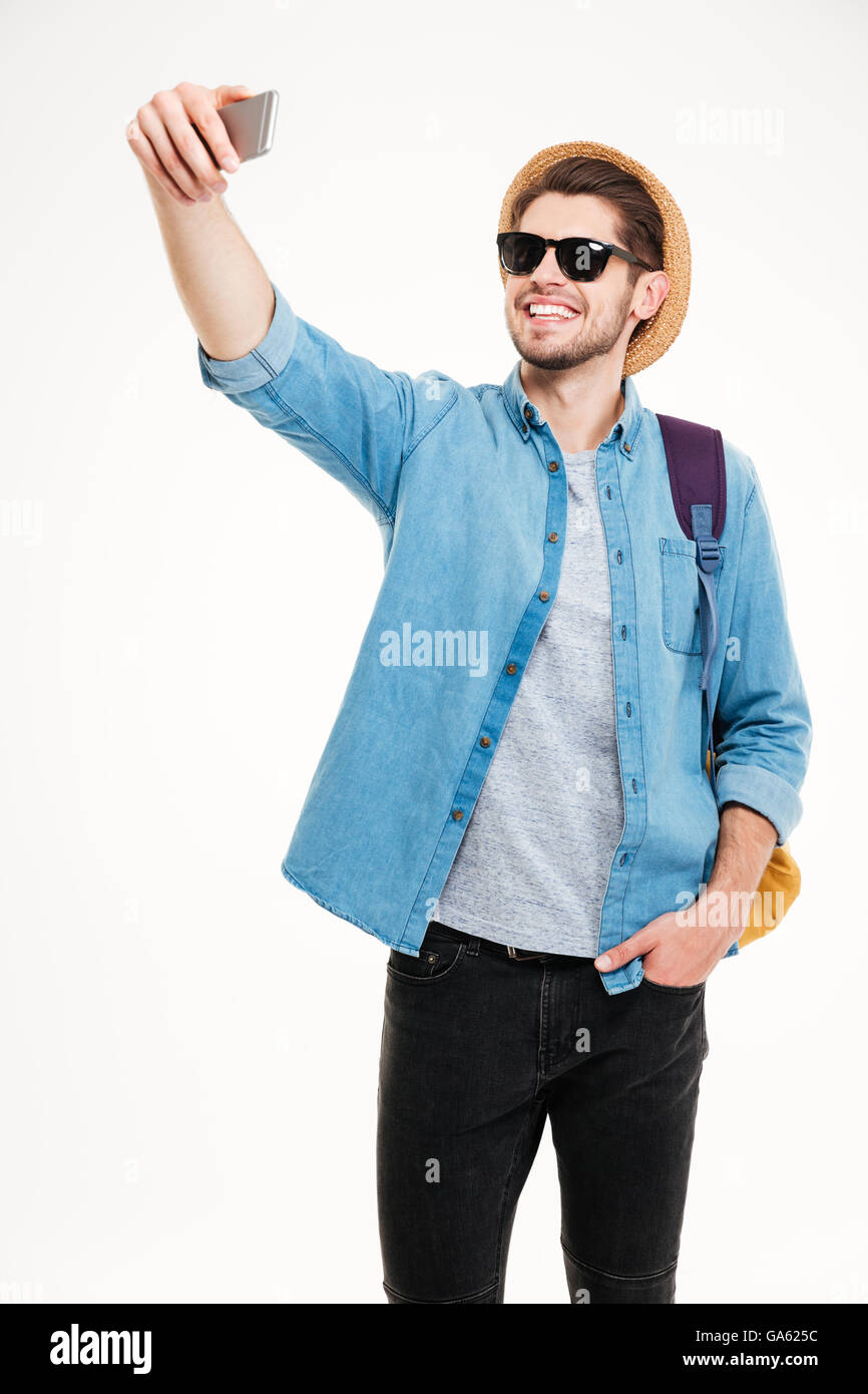 Fröhliche attraktiver junger Mann mit Rucksack nehmen Selfie mit Handy Stockfoto