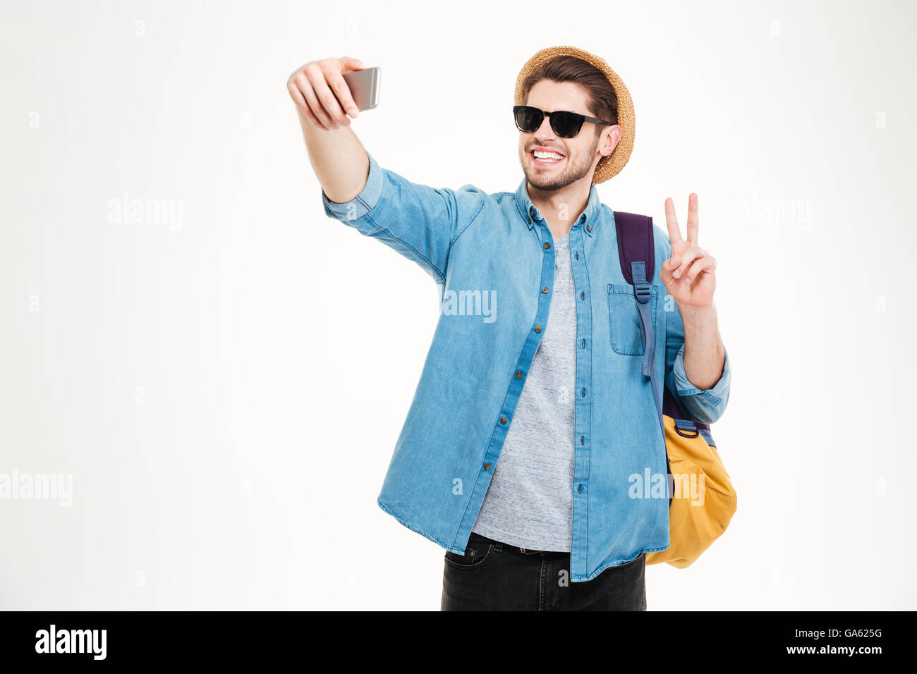 Glücklich Jüngling in Sonnenbrille mit Rucksack macht Selfie und mit Peace-Zeichen Stockfoto