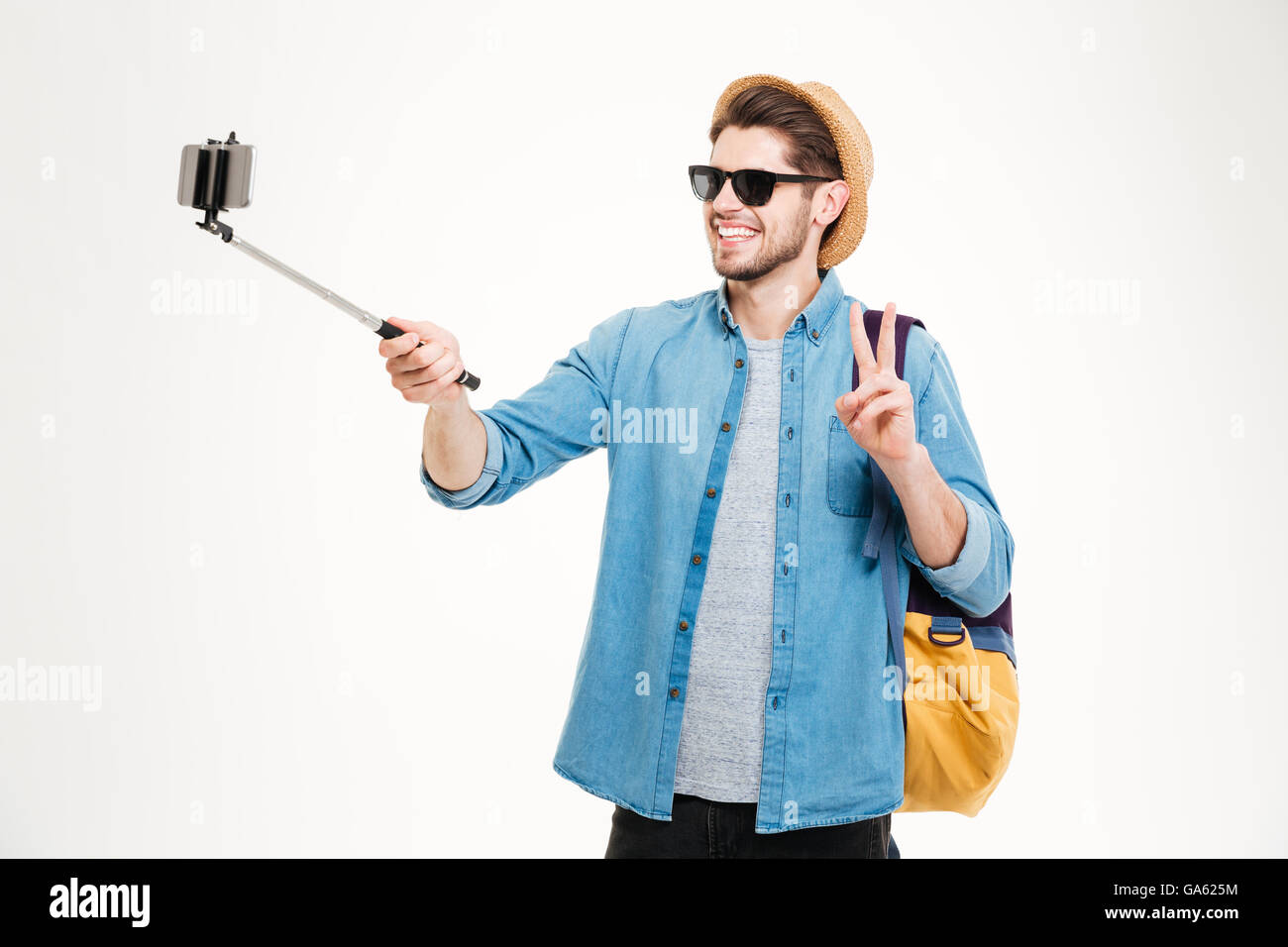 Fröhlichen jungen Mann mit Rucksack fotografieren mit Handys und Selfie stick Stockfoto