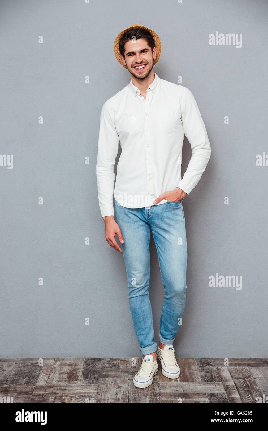 Fröhliche attraktive junge Mann stehen und Lächeln über grauen Hintergrund Stockfoto