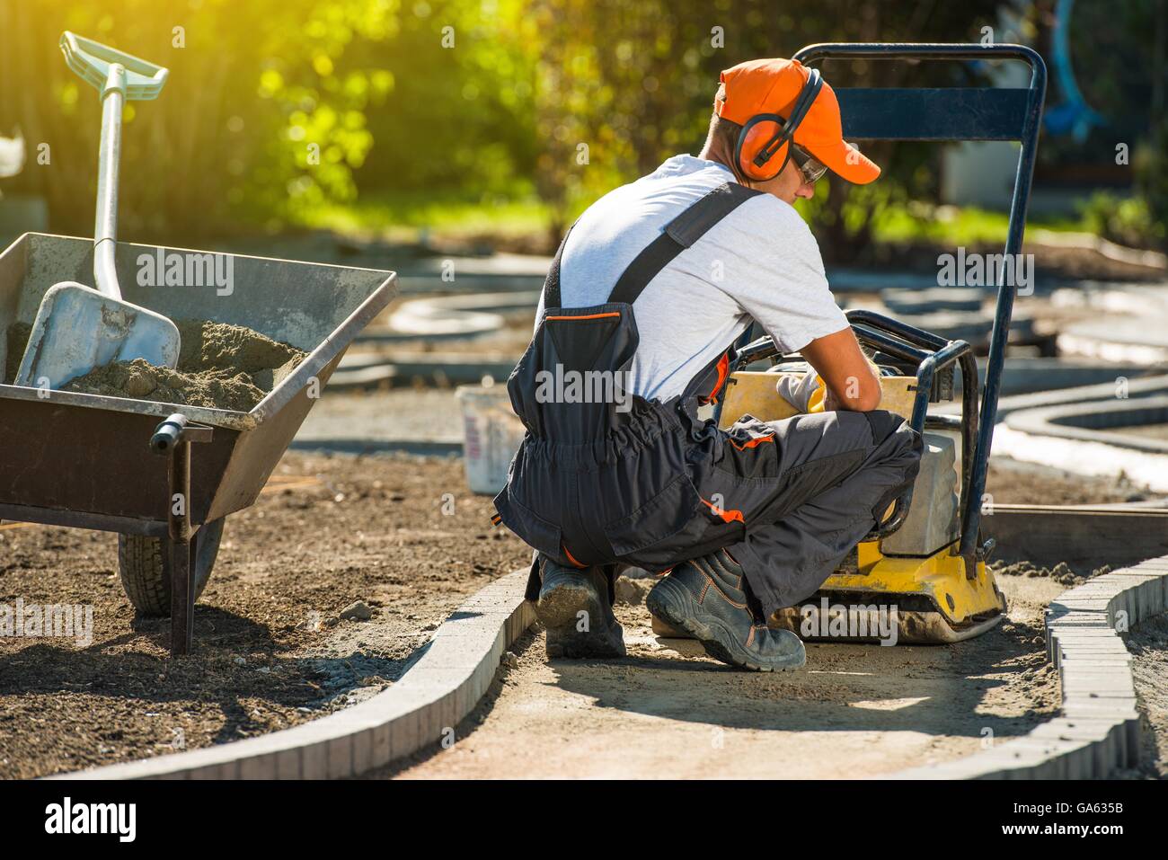 Platte-Müllpresse-Ziegelstein-arbeiten. Professionelle Backstein Fertiger und seine Plattenverdichter am Arbeitsplatz. Stockfoto