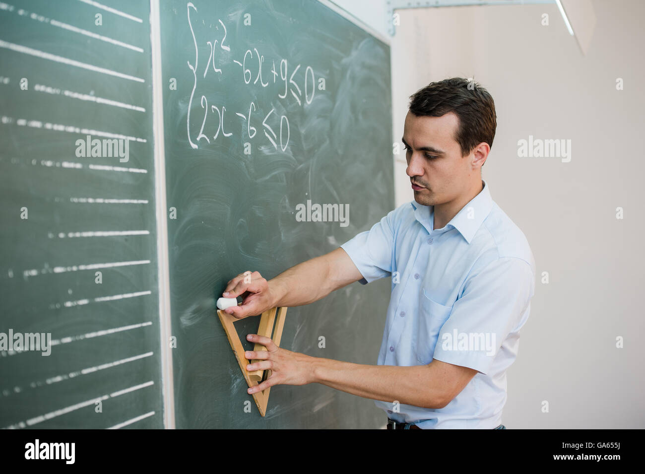 Junge Lehrer oder Schüler zeichnen an einer Tafel mit Formel Dreieck Stockfoto